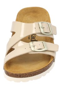 Sandale en cuir verni beige avec deux sangles ajustables et boucles en argent ; semelle en liège contournée ; semelle en caoutchouc blanche.