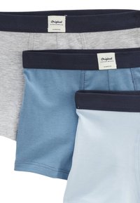 Trois paires de boxers pour hommes : gris, bleu foncé et bleu clair. Chacun est doté d'une ceinture bleu foncé avec une étiquette indiquant "Original Underwear".