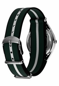 Timex sat s zelenim tekstilnim remenom s dvije bijele pruge, srebrnom kopčom i kućištem od nehrđajućeg čelika, koji prikazuje moderni dizajn.