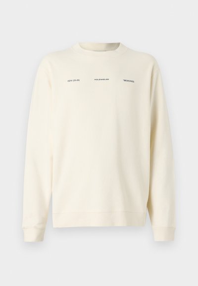 Felpa color crema con scollo rotondo, maniche lunghe e testo stampato in nero. Tessuto morbido con vestibilità comoda.