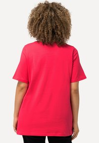 Camiseta de algodón de color rosa brillante con mangas cortas y un ajuste holgado, que presenta un escote redondeado y una textura suave y lisa.
