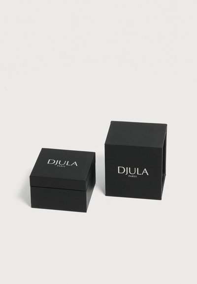 Deux boîtes à bijoux carrées noires, l'une fermée et l'autre ouverte, toutes deux avec "DJULA PARIS" imprimé en blanc sur les couvercles sur un fond blanc.