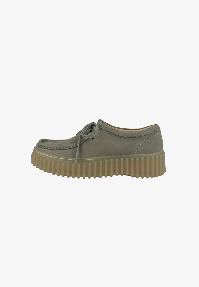Chaussure en daim vert à lacets avec semelle en caoutchouc épaisse et nervurée et détails cousus le long de l'orteil et des côtés.