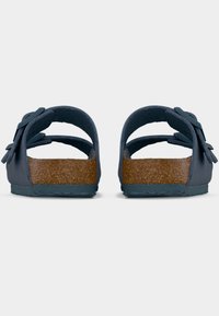 Σκούρα μπλε σανδάλια με δύο φαρδιές λουρίδες, που διαθέτουν πάτο από φελλό και υφή στην σόλα. Μαλακό, ευέλικτο υλικό με φιόγκο διακοσμητικό στις λουρίδες.