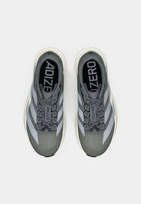 Zapatillas deportivas grises con una parte superior texturizada y franjas en gris claro contrastante, con una puntera redonda y suelas blancas planas.