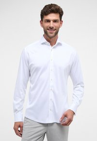 Witte langelijfknop-shirt met een brede kraag en lichtbruine knopen, gemaakt van gladde stof met een lichte glans.