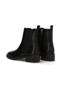 Botines de cuero negro con textura suave, paneles laterales elásticos, cremallera trasera y tacón grueso. Diseño clásico de botín Chelsea.