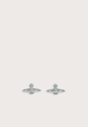 Boucles d'oreilles clous ton argent en forme de planète avec anneaux, ornées de petits cristaux bleus et transparents.
