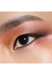 Nahaufnahme eines Auges mit warmen Lidschatten in Pfirsich- und Kupfertönen, definiertem Eyeliner und dunkelbraunem Iriss, die Textur und Farbe hervorhebend.