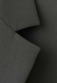 Tessuto grigio scuro con una superficie liscia e strutturata, caratterizzato da pieghe nette e un aspetto ordinato, che mette in risalto un design solido e pulito.