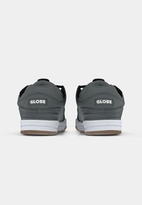 Grijze sneakers met zwarte accenten, gepolsterde kraag, witte middenzool en rubberen buitenzool. Kenmerkt "GLOBE" branding op de hiel.