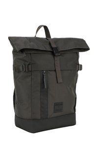 Zaino in verde oliva scuro con chiusura a roll-top, spallacci regolabili, tasca frontale con zip e tessuto testurizzato. Presenta una base nera uniforme.