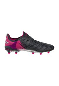 Voetbalschoen heeft een zwarte bovenkant met een gestructureerd patroon, roze accenten op de hak en zool, en conische noppen voor grip.