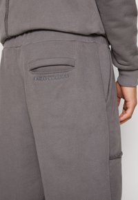 Grijze sweatpants met een achterzak met een horizontale opening en geborduurd "CARLO COLUCCI" logo erboven, gemaakt van zachte stof.