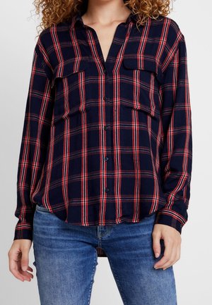 Camicia button-up a quadri blu navy con strisce rosse e bianche, due taschini sul petto e maniche lunghe, realizzata in un tessuto morbido.