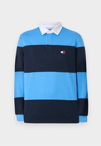 Langermet polo skjorte i blå og marine striper, med hvit krage og en liten logo på brystet. Laget av en myk bomullsblanding.