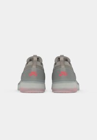 Nike tenisice sa glatkim sivim gornjim dijelom, ružičastim logotipom i gradijentnom potplatom koji prelazi iz plave u ružičastu. Imaju trakicu za povlačenje na peti.