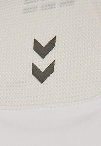 Wit textiel met een gestructureerd patroon en twee zwarte naar beneden wijzende chevrons. Minimalistisch ontwerp met contrasterende kleuren.