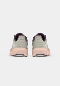 Des chaussures de course avec un dessus gris et blanc, des accents lavande, une semelle rose pâle, une forme arrondie et un dos texturé pour une meilleure adhérence.