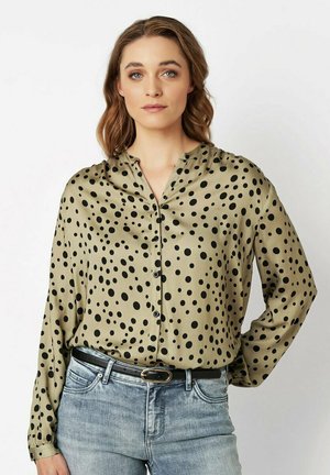 Langärmlige, olivgrüne Bluse aus Satin mit V-Ausschnitt und schwarzen Punkten, die vorn mit Knöpfen geschlossen wird.