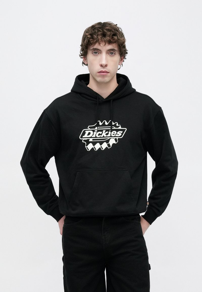 Sudadera negra de algodón, con un gran logo blanco en el centro. Incluye un bolsillo frontal y una capucha con cordón ajustable.