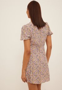 Violetti kukkamekko, jossa on puffihihat, istuva bodice ja levenevä hame. Sisältää pienen kukkakuosin keltaisena, vaaleanpunaisena ja vihreänä.