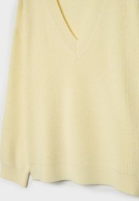 Żółty sweter z prążkowanej dzianiny z dekoltem w serek i krótkimi rękawami, charakteryzujący się miękką fakturą i luźnym krojem.