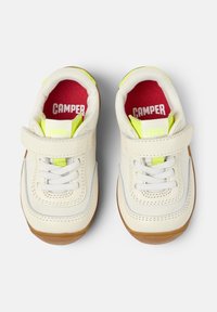 Sneaker bianche con una fascia in velcro, dettagli grigi e suole di gomma. Fodera interna verde brillante e rossa con il nome del marchio "CAMPER" visibile.