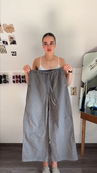 Pantaloni largi, gri deschis, din bumbac, cu un talie elastică și șnur de ajustare și buzunare laterale. Textură fină.