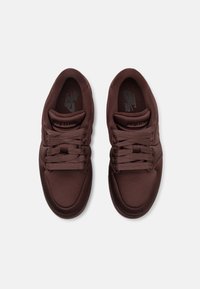 Paire de baskets Nike Air Jordan marron foncé avec lacets noués, vues de dessus sur un fond gris clair.