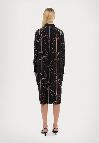 Čierne šaty s kvetinovým vzorom obrysom v viacfarebných líniách, s golierom a dlhými rukávmi. Mäkko sa vzďaľujúci materiál.