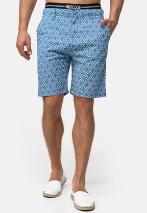 Shorts bleus à motif avec des formes de diamant, fabriqués en tissu léger, dotés de poches et d'une taille élastique avec une marque noire.