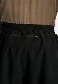 Sorte letvægts shorts med elastik i taljen. Har en lille lynlåslomme på ryggen, lavet af struktureret, åndbart stof.