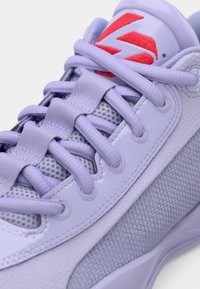 Fioletowy sneaker z siateczkową cholewką, gładkimi naszywkami, teksturowanymi akcentami, płaskimi sznurowadłami oraz czerwoną logo na języku.