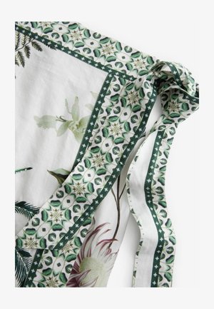 Šal s cvjetnim uzorkom koji ima bijelu podlogu s zelenim naglascima i detaljima, obrubljen dekorativnim zelenim i bijelim uzorkovanim rubom.