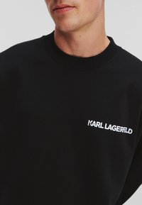 Sudadera negra de mezcla de algodón, con cuello redondo acanalado y el logo bordado en blanco "KARL LAGERFELD" en el lado izquierdo del pecho.
