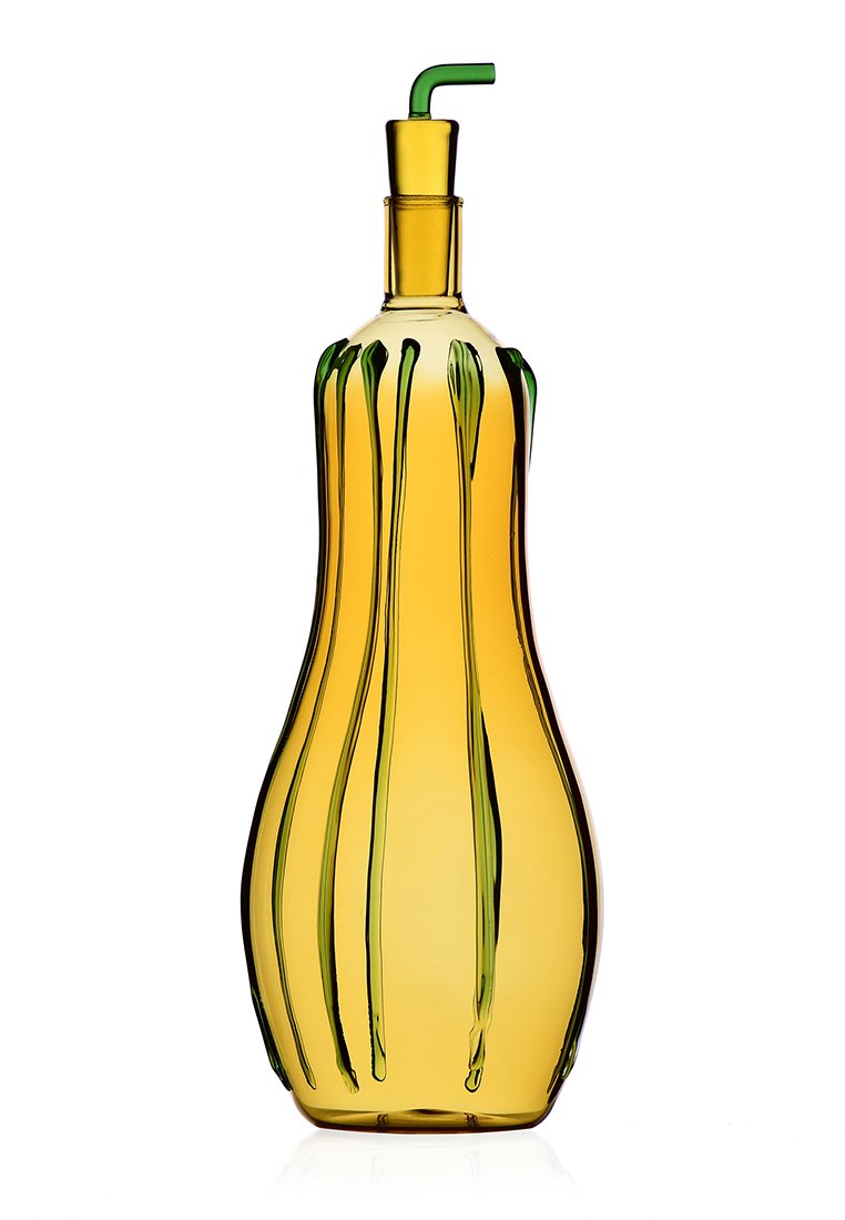 Żółta szklana butelka o falistym, wydłużonym kształcie, z zielonymi smugami. U góry zakończona metalowym dozownikiem i cienką zieloną słomką.