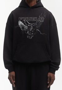 Felpa nera con cappuccio, grafica di un'aquila e testo "FAVELA". Presenta una tasca frontale e maniche con polsini. Tessuto morbido con vestibilità comoda.