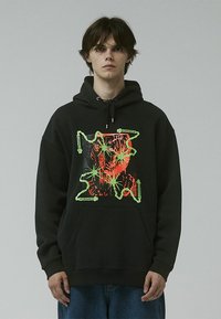 Black hoodie with a front graphic featuring red and green design elements. Material appears soft; includes a kangaroo pocket and drawstring hood.