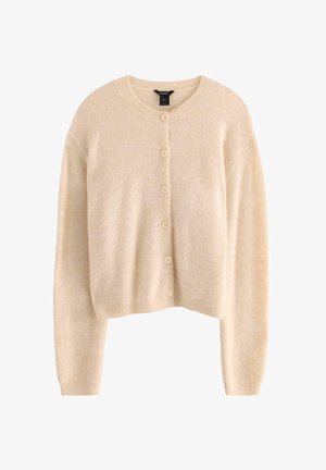 Beige lyhyt villatakki, joka on valmistettu pehmeästä kankaasta, jossa on pyöreä kaula-aukko, pitkät hihat ja kuusi samansävyistä nappia edessä.