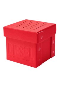Boîte en plastique rouge de forme carrée, avec une surface texturée et un couvercle perforé. Présente l'inscription en relief "DIESEL POUR UNE VIE RÉUSSIE".
