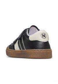 Sneaker in pelle nera con accenti bianchi, una chiusura in velcro, dettagli di cucitura a zigzag e suola in gomma. Caratterizzato da un logo sul tallone.