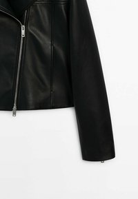 Veste noire en cuir synthétique avec fermeture éclair argentée à l'avant et manches longues, présentée sur fond blanc.