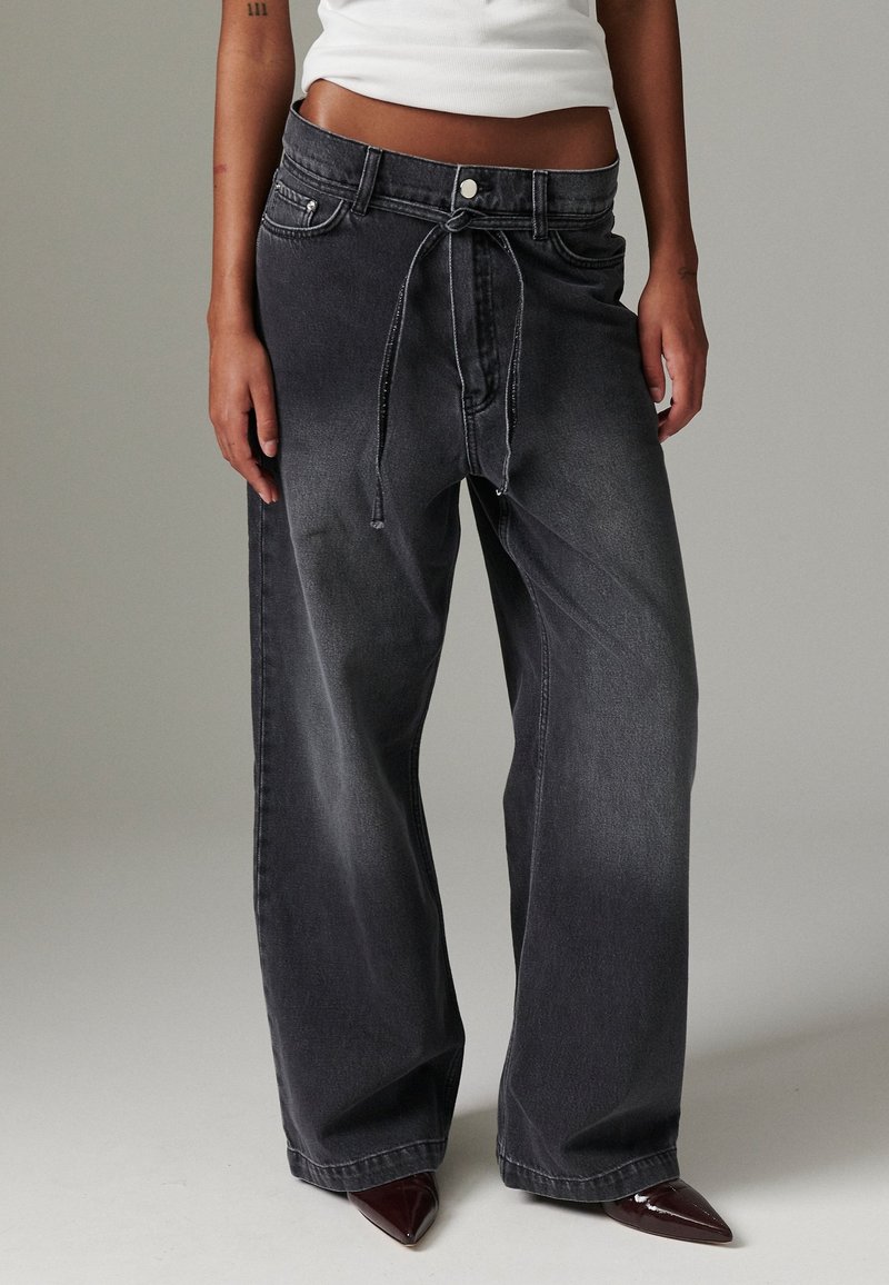 Černé džíny s širokými nohavicemi z denimu se zfadedovým efektem, elastickým pasem se šňůrkou, předními kapsami a kontrastními detaily stehu.