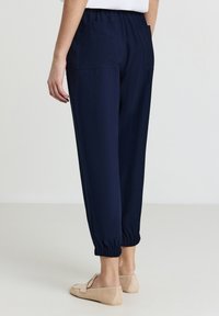Pantalons de jogging marine en matériau léger, avec une taille élastique, des ourlets resserrés et deux poches arrière.