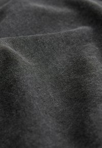 Black textured fabric with a fine weave, showing smooth, soft surface and subtle sheen, reflecting light at various angles.