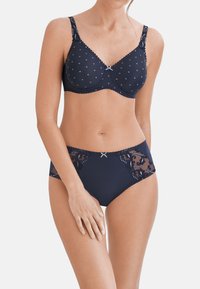 Marineblauwe beha en hoogopgesneden slipset. De beha heeft stippen, kanten accenten en verstelbare banden. De slip heeft kantdetails aan de zijkanten.