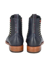 Skórzane botki za kostkę w kolorze granatowym z paskowymi panelami materiałowymi, dekoracyjnym przeszyciem, wzniesionymi akcentami i drewnianymi obcasami. Zawierają szczegółowe perforacje.