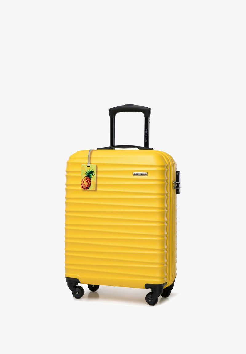 Gele hard-shell koffer met ribbelstructuur, zwarte uitschuifbare handgreep en wielen. Inclusief een label met een ananasafbeelding.