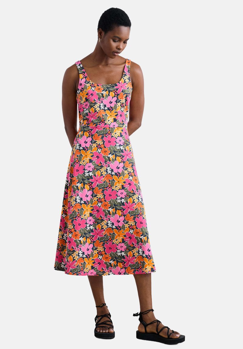Robe florale en rose, orange et vert, avec un décolleté carré, de larges bretelles et un ourlet évasé ; assortie à des sandales noires à lanières.